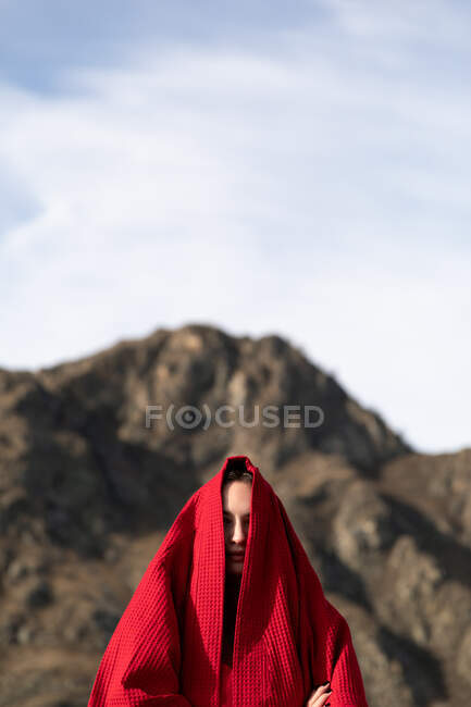 Mujer con un albornoz en la cabeza en la cabeza cerca de la montaña - foto de stock