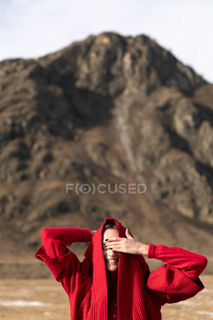 Mulher sorrindo em vermelho casaco fechado mão olhos — Fotografia de Stock