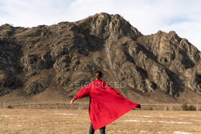 Femme de dos dans un peignoir rouge court à côté de la montagne — Photo de stock