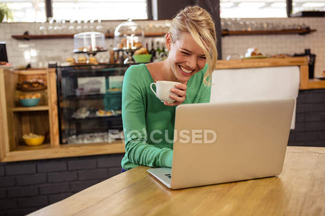 Frau trinkt Kaffee und benutzt Laptop — Stockfoto