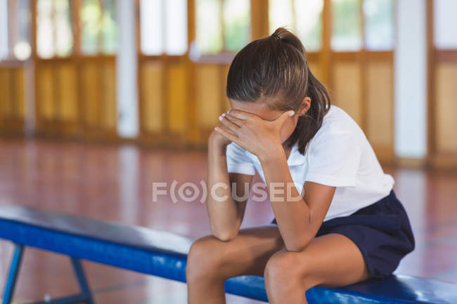 Sad schoolgirl sitting alone in basketball court — Stock Photo