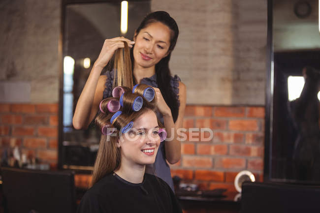 Female hairdresser styling customers hair — Stock Photo