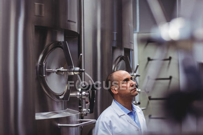 Fabricante de cervejaria olhando para tanques de armazenamento — Fotografia de Stock