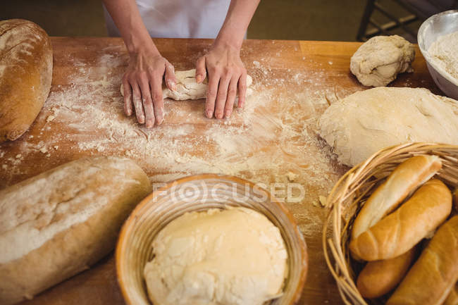 Mains de boulangère pétrissant une pâte — Photo de stock