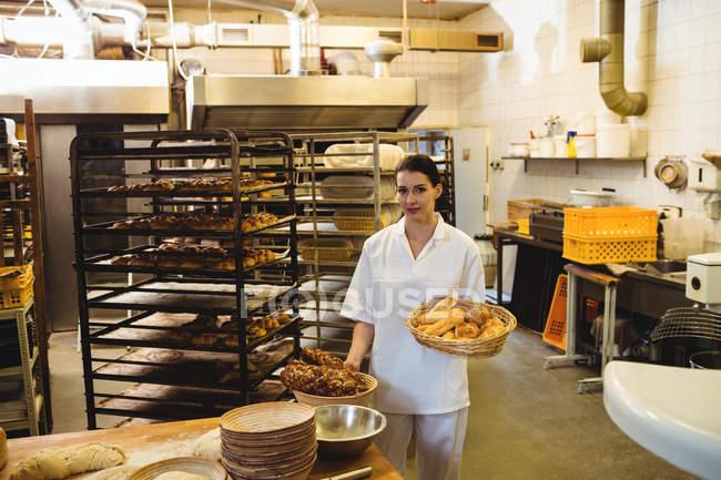Boulanger femelle tenant panier d'aliments sucrés — Photo de stock