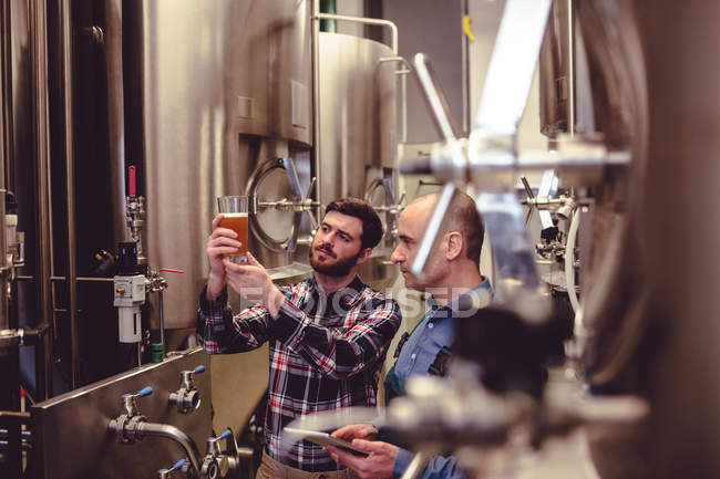 Proprietário e trabalhador examinando cerveja em vidro — Fotografia de Stock