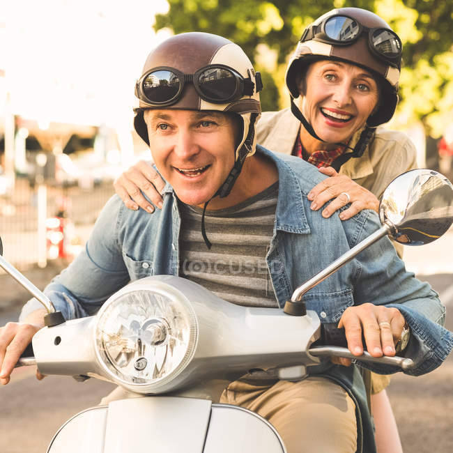 Glückliches älteres Paar auf einem Motorroller in der Stadt — Stockfoto