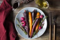 Carote arrosto e alla griglia con ravanello e rosmarino sul piatto — Foto stock