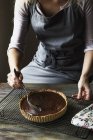 Частковий вигляд жінки, що поливає шоколад для Ganache Tart на охолоджувальній стійці — стокове фото