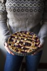 Cropped image of woman holding berry pie with a lattice top — Stock Photo