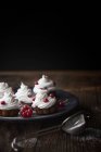 Primer plano de cupcakes recién horneados decorados con grosellas rojas en el plato - foto de stock