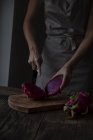 Cropped image of woman slicing dragonfruit on chopping board — Stock Photo