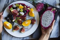Composição de frutas fatiadas contém com figos, dragonfruit, uva e laranjas no prato — Fotografia de Stock