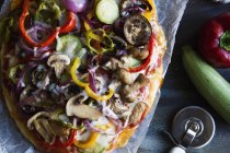Vista superior de la pizza vegetariana en el estante de enfriamiento con verduras en la mesa - foto de stock
