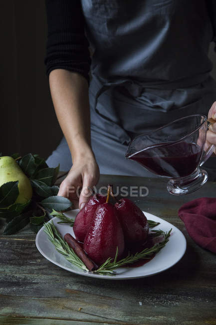 Частковий вигляд жінки, що поливає прянощі червоне вино, відбиті груші — стокове фото