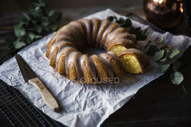 Close up of classic lemon cake with vanilla glaze on cooling rack — Stock Photo