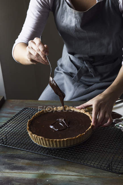 Vista parcial da mulher derramando chocolate para Ganache Tart no rack de refrigeração — Fotografia de Stock