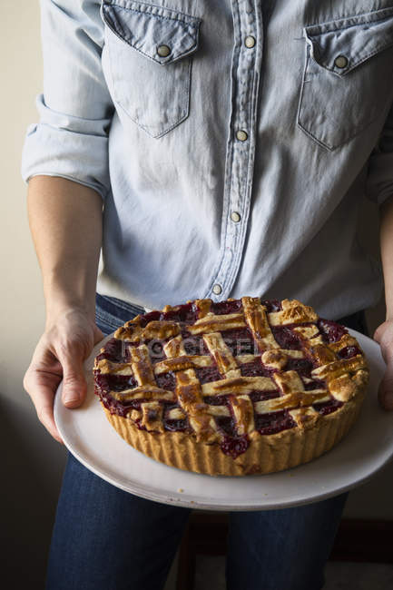 Cropped image of woman holding berry pie with a lattice top — Stock Photo