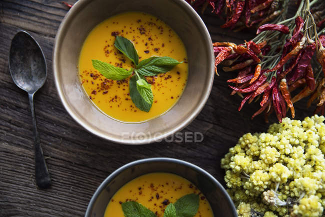 Una ciotola di zuppa di verdure in ceramica con foglie di basilico sul tavolo di legno — Foto stock
