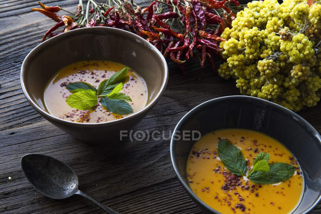 Керамічні миски Вегетаріанського супу з листям базиліка на дерев'яному столі — стокове фото