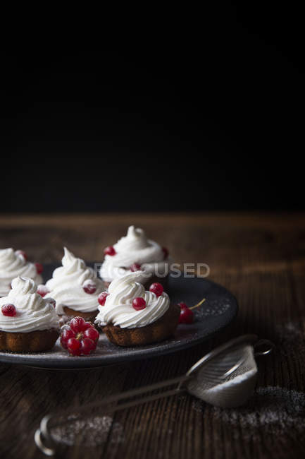 Крупним планом свіжоспечені кекси, прикрашені червоною смородиною на тарілці — стокове фото