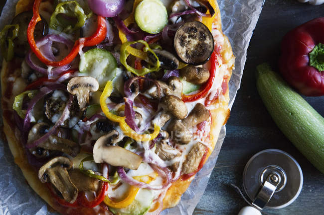 Вид зверху вегетаріанської піци на охолоджувальній стійці з овочами на столі — стокове фото