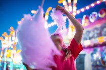 Little girl eating candyfloss in the summer amusement park — Stock Photo