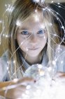 Adorable blonde girl with blue eyes wearing christmas lights — Stock Photo