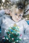 Beautiful blonde preteen girl with blue eyes lying on bed with illuminated christmas lights — Stock Photo