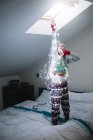 Blonde preteen girl decorating bedroom with illuminated Christmas garland — Stock Photo