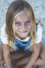 Beautiful blonde preteen girl with blue eyes sitting on floor and looking at camera — Stock Photo