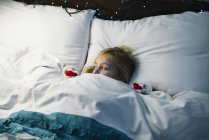 Petite fille au lit en attendant santa claus — Photo de stock