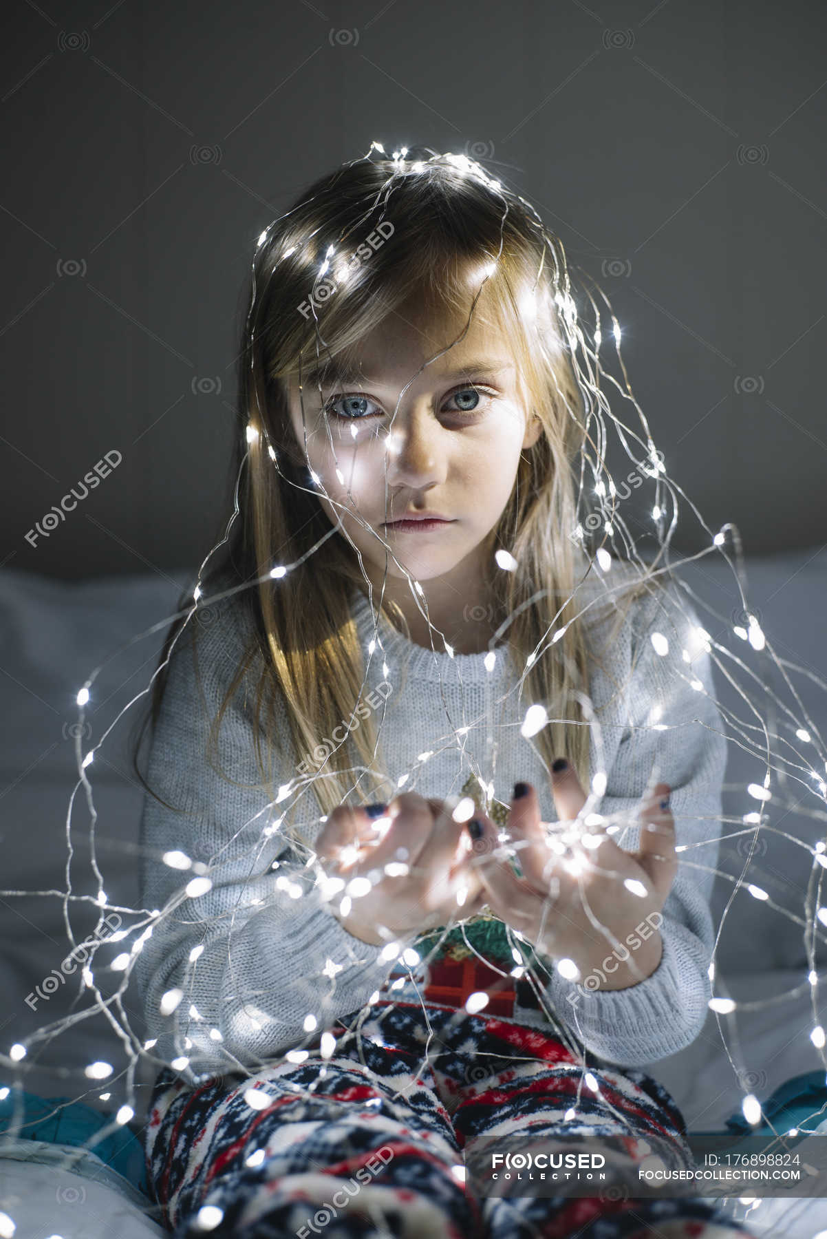 Beautiful blonde preteen girl wearing illuminated christmas garland ...