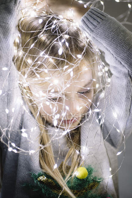 Cute blonde preteen girl with illuminated christmas lights on head — Stock Photo