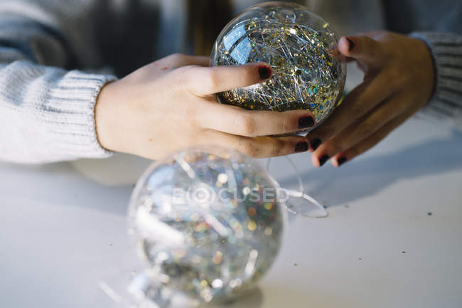 Частковий вигляд рук маленької дівчинки з різдвяними кульками — стокове фото