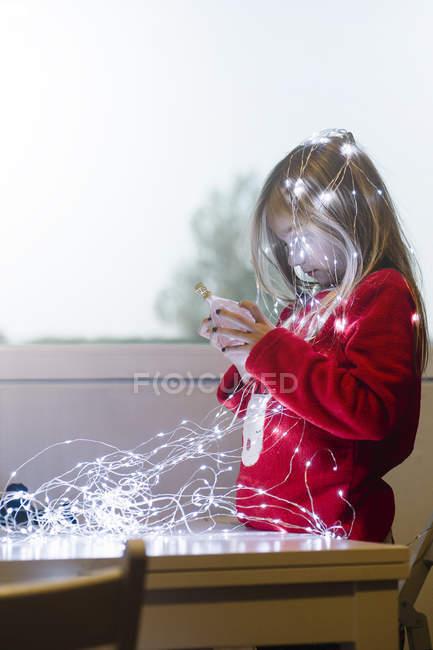 Loira preteen menina olhando para lâmpada e sala de decoração com guirlanda de Natal iluminado — Fotografia de Stock