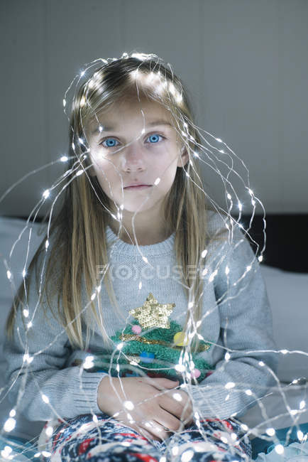 Schöne blonde preteen Mädchen tragen beleuchtete Weihnachtsgirlanden mit glühenden Glühbirnen — Stockfoto