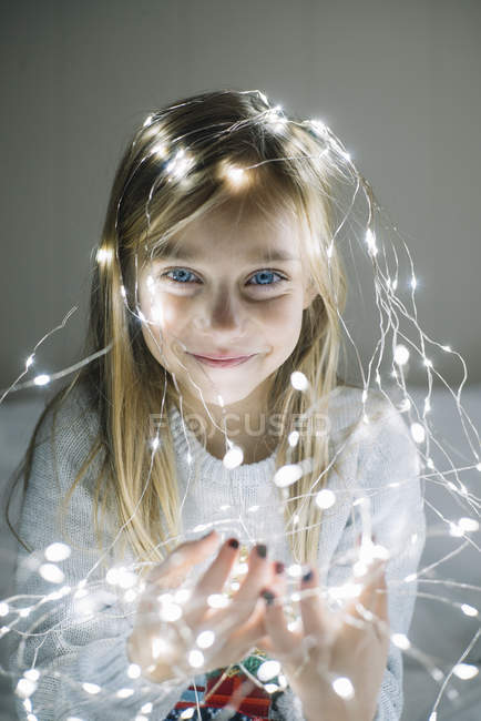 Adorabile ragazza bionda con gli occhi azzurri indossando luci di Natale — Foto stock