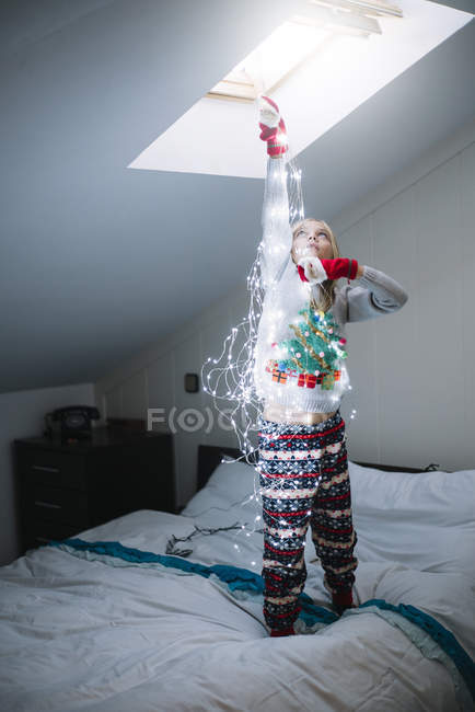 Rubia chica preadolescente decoración dormitorio con guirnalda de Navidad iluminada - foto de stock