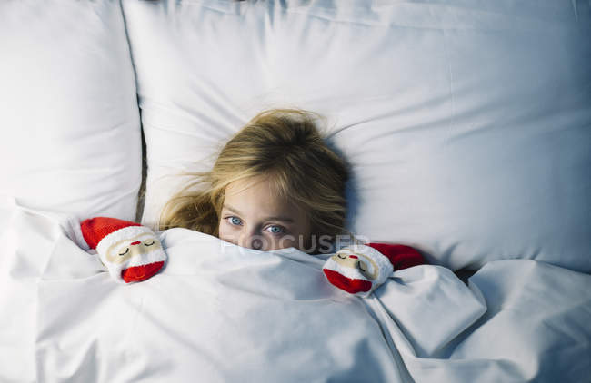 Linda niña acostada debajo de la manta en la cama y esperando a Santa Claus - foto de stock