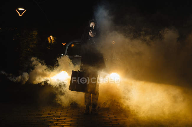 Mujeres con maleta delante del coche con humo - foto de stock