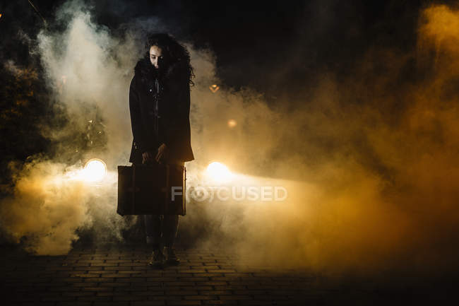 Женщин с чемоданом перед машиной с дымом — стоковое фото