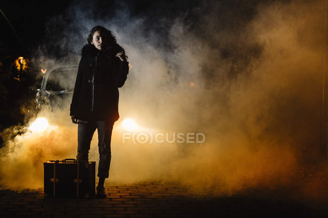 Women with suitcase in front of the car with smoke — Stock Photo