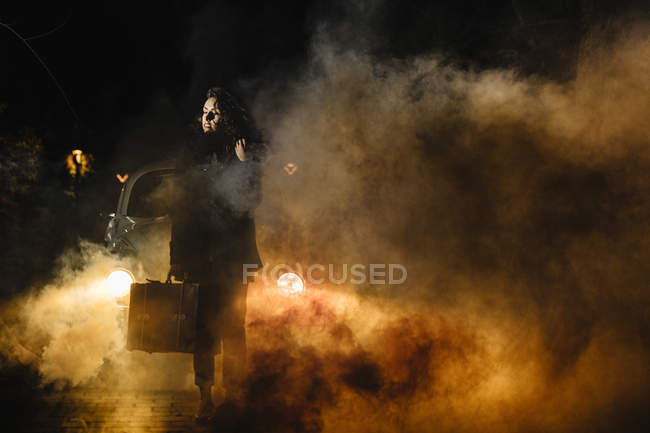 Women with suitcase in front of the car with smoke — Stock Photo
