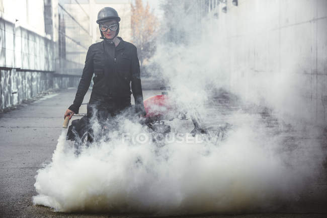 Motociclista donna in strada che tiene una fiamma fumogena — Foto stock