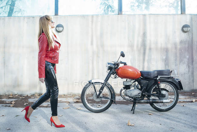 Mujer moto caminar junto a la motocicleta - foto de stock