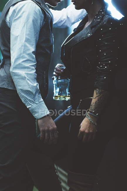 Bild eines Mannes in klassischer Kleidung und einer tätowierten Frau, die eine Flasche dicht nebeneinander hält — Stockfoto