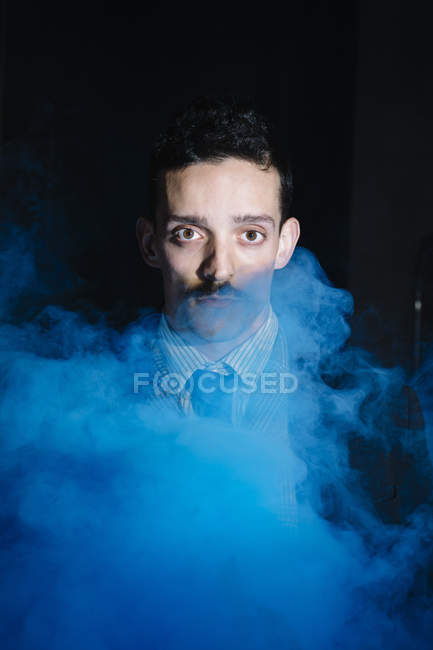 Porträt eines Mannes in klassischer Kleidung, der durch Dampf in die Kamera blickt — Stockfoto