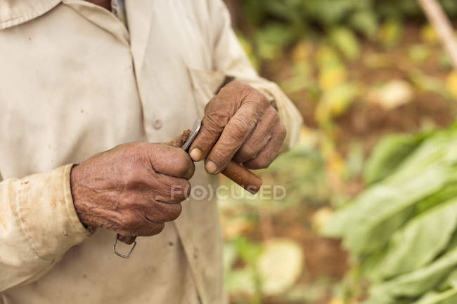 Uomo che taglia un sigaro con il coltello tradizionale di Cuba — Foto stock