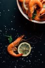 Vue surélevée des tranches de citron, feuilles de menthe, crevettes et assiette sur table avec sel — Photo de stock